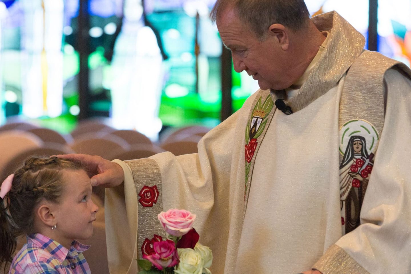 Fr. Bob Colaresi blesses young child at St. Therese Feast Day