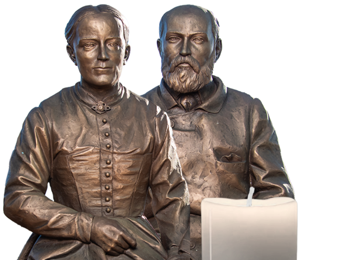 Bronze statue of Saints Louis and Zelie Martin with a candle
